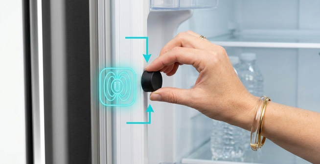 A clean, modern vector style technical illustration (16:9 aspect ratio) showing how to bypass a refrigerator door sensor. The image shows a close up of a sleek stainless steel refrigerator door slightly open. An arrow points to the hidden magnetic reed switch inside the door frame. A small, black, rubber coated neodymium magnet is being placed over the sensor area. Simple, elegant line art with a limited color palette of gray, white, and a highlight color of bright blue for the magnet and sensor. No text in the image.